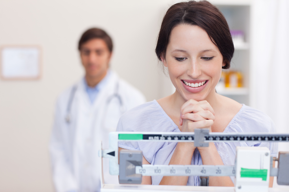 Smiling young woman excited about the scale